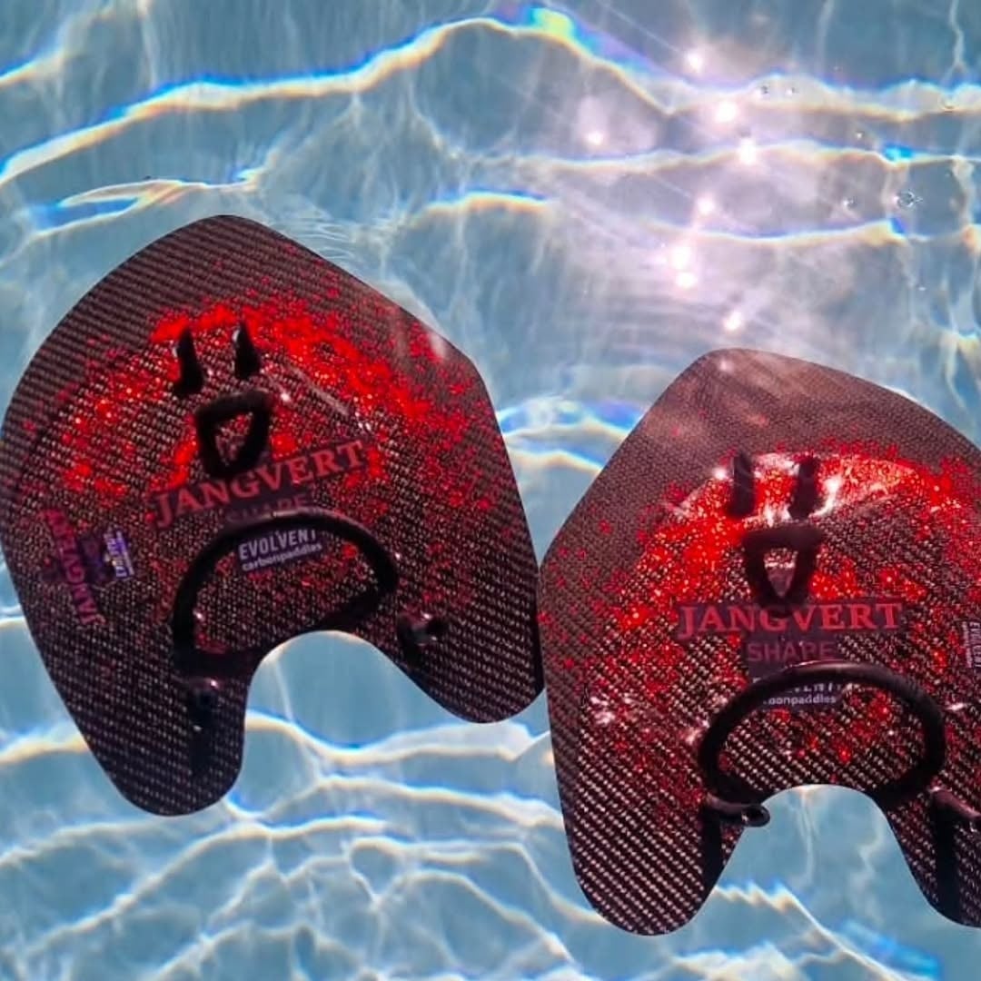 CC Jangvert Shape carbonpaddlar glittrar röda under vattnet i en pool, svart carbon med röd stänkdesign